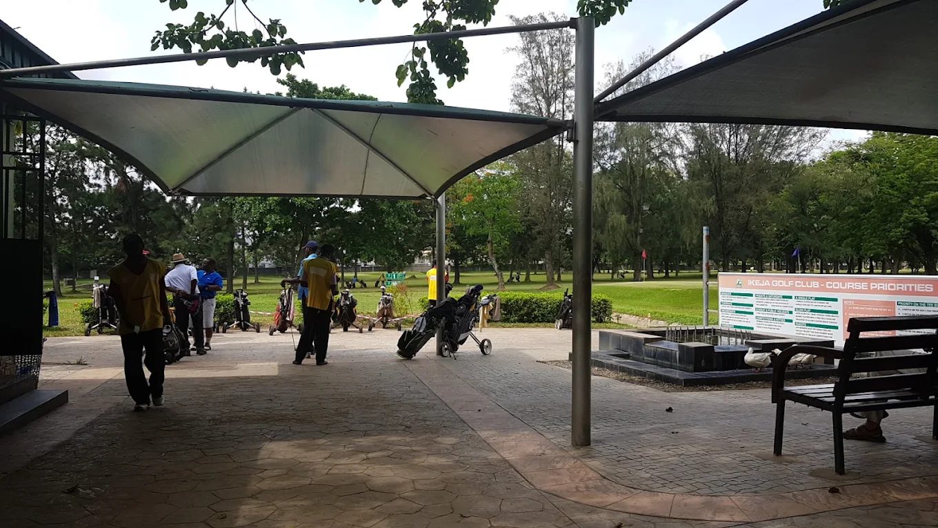 Golfers gathering under the first-tee shelter at Ikeja Golf Club, with the course beyond